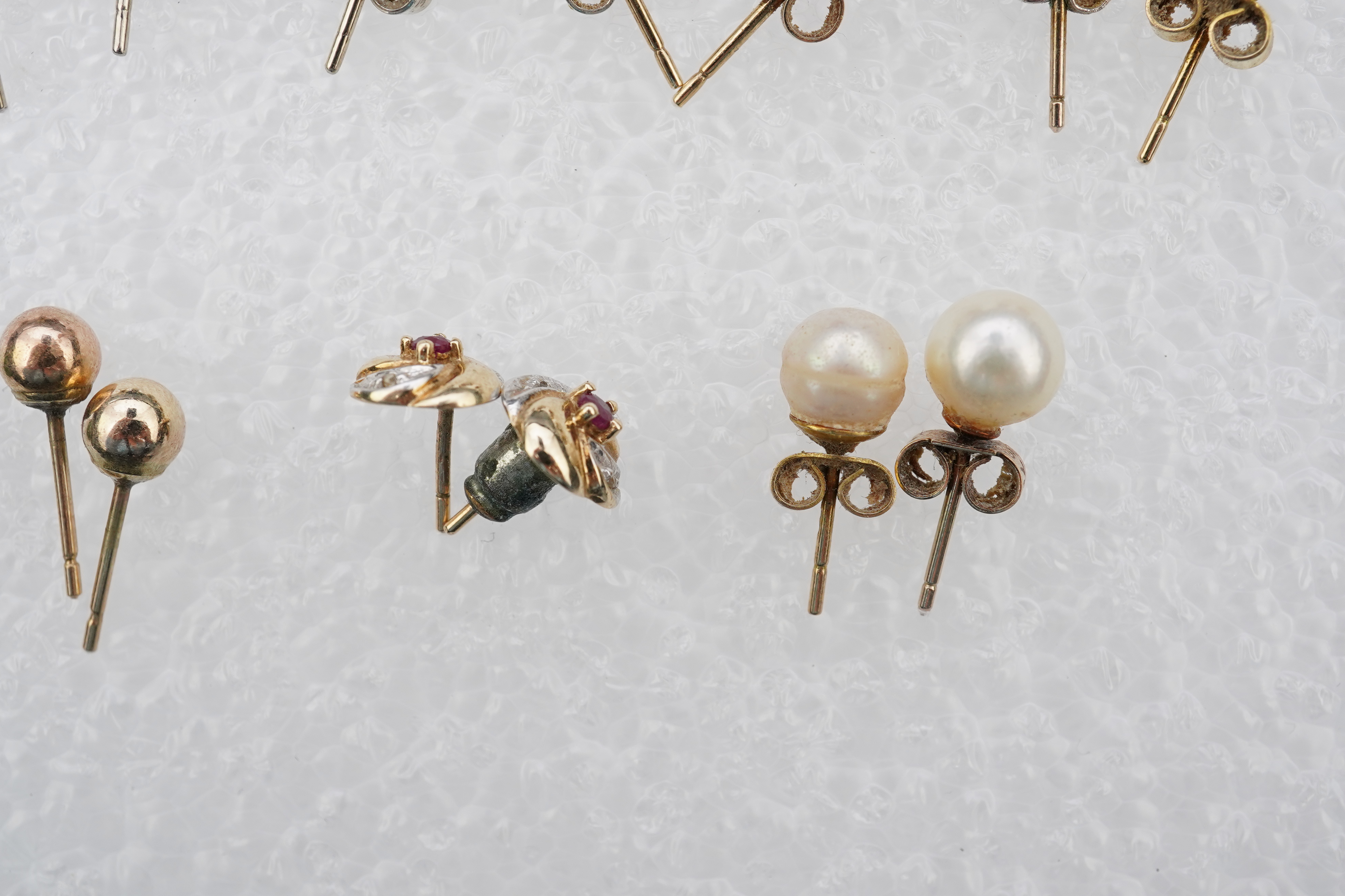 Four assorted pairs of 9ct and gem set ear studs including peridot and cultured pearl, together with three other assorted pairs yellow or white metal ear studs and two odd ear studs.
